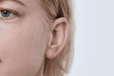 Appareil auditif Oticon More, modèle miniRITE R, couleur Gris clair, photo prise de face sous un angle de 45°, Gros plan sur l'oreille, Femme Appareils auditifs avec service illimité Auzen