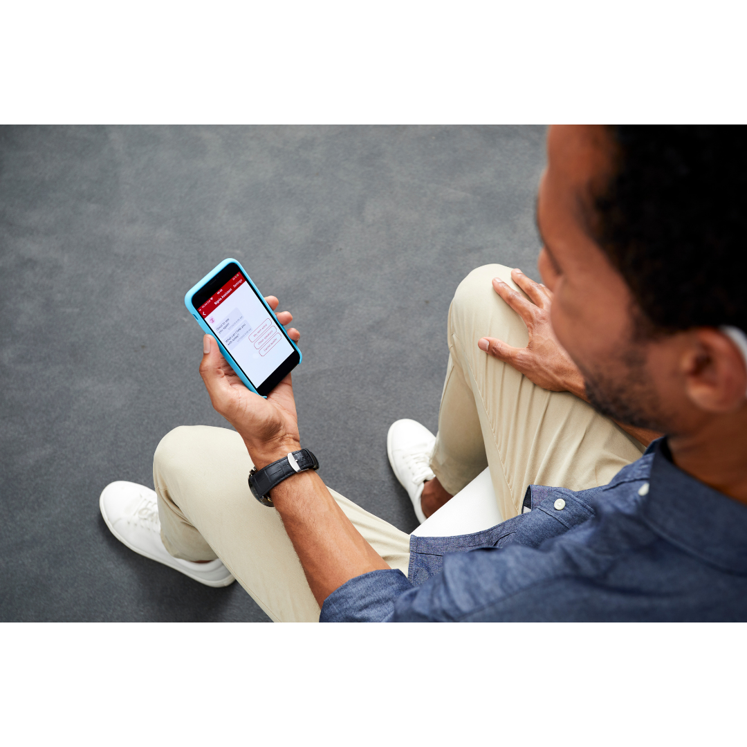 A young middle-aged man is looking at his smartphone and having the apllication open to control his Signia Styletto hearing aids