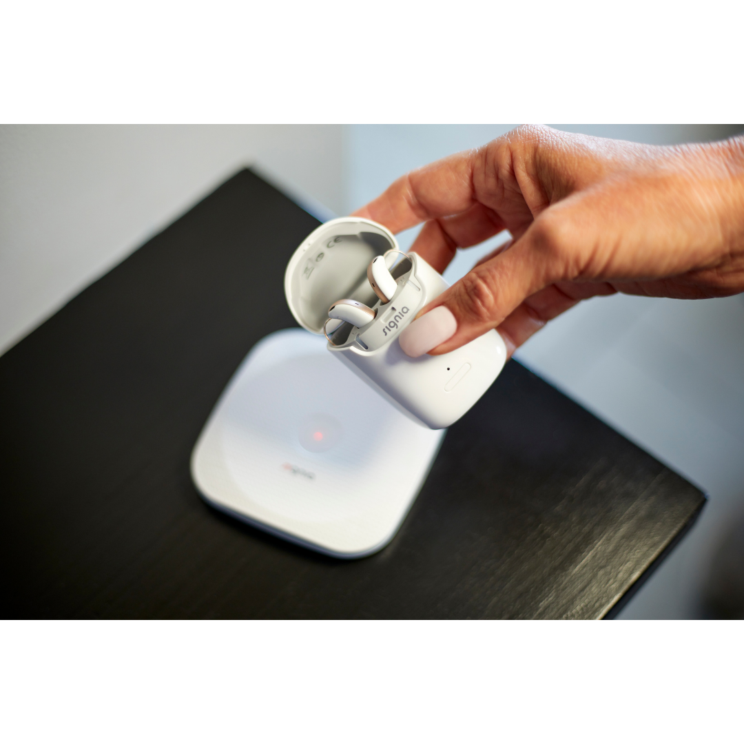 A woman is placing the portable, nomad charging case on the charging pad